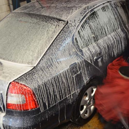 vehículo Skoda azul oscuro entrando en el tunel de lavado una vez enjabonado