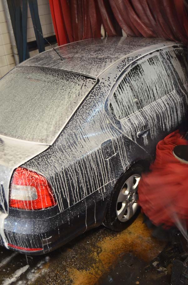 vehículo Skoda azul oscuro entrando en el tunel de lavado una vez enjabonado